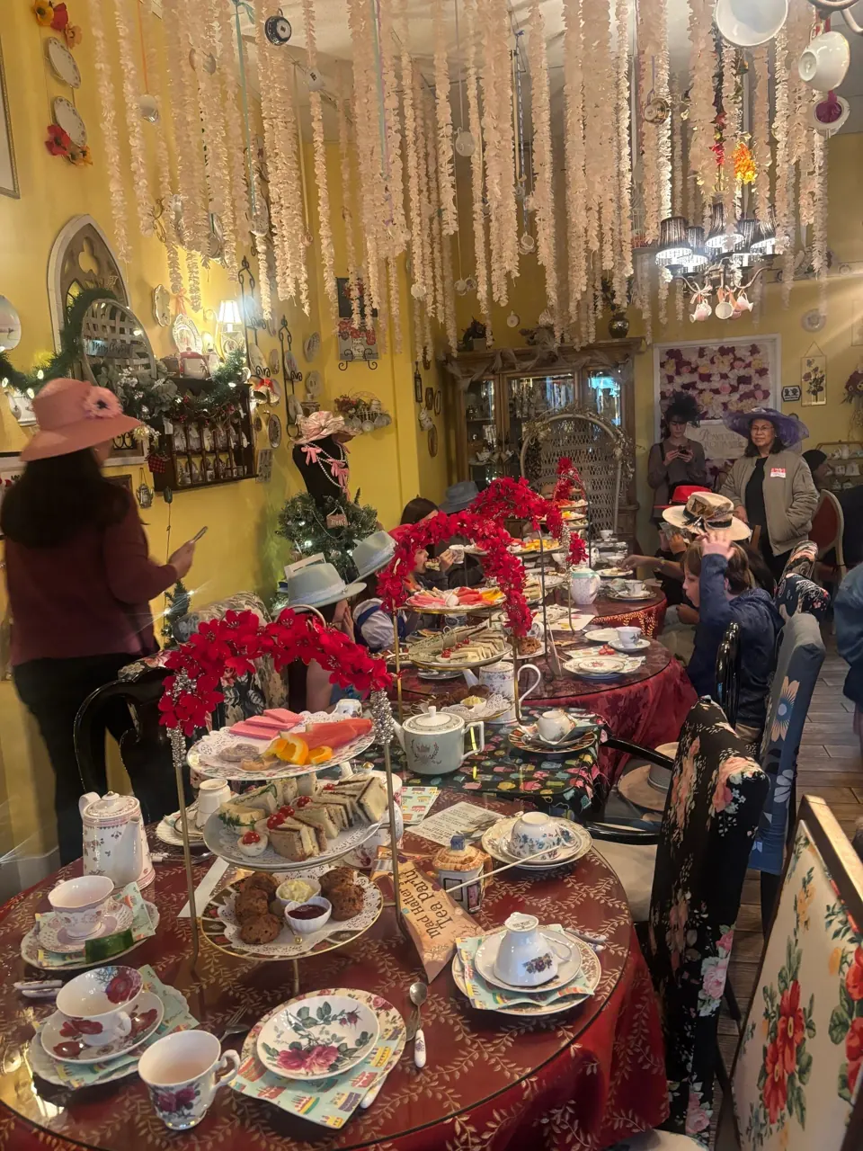 Elegant tea party setup with floral teacups and tiered trays of treats.