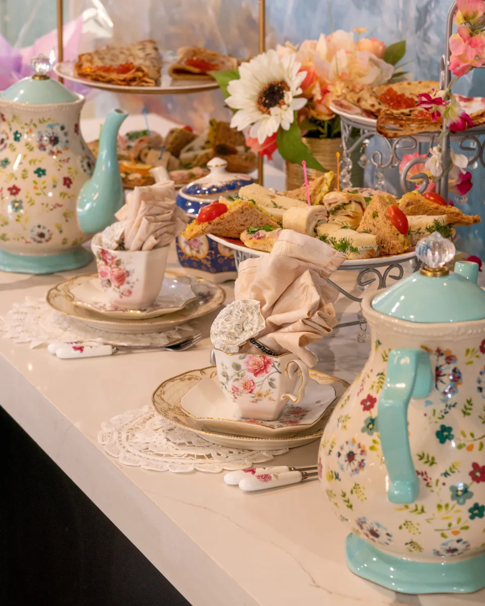 Afternoon tea table with floral china, sandwiches, teapots and fresh flowers at The Tea Terrace