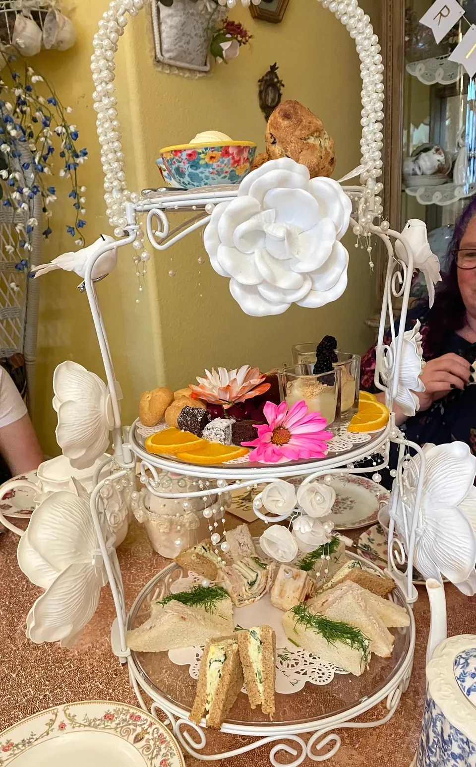 Three-tier tea stand arranged with savory bites, pastries and flowers